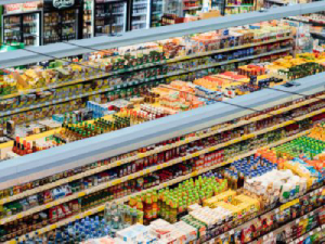 Lorong supermarket dengan rak-rak penuh makanan yang diatur berdasarkan jenis dan warna.